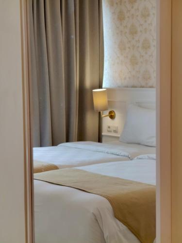 two beds in a hotel room with a window at The Cube Hotel Malioboro, Azana Hotels Collection in Yogyakarta