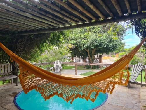 a hammock on a patio with a pool at Chalés Refúgio Fortim in Fortim