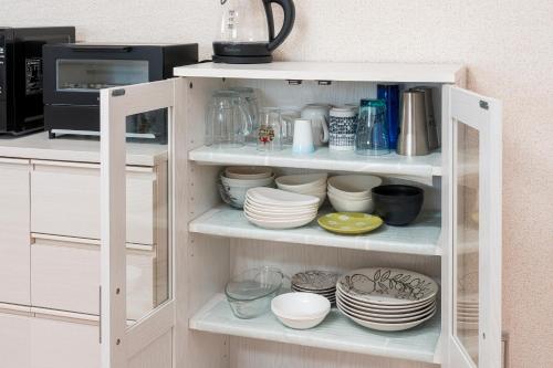 a white cabinet filled with plates and dishes at AOMORI HORIZON 5 minutes walk from Tsutsui Station 筒井 in Aomori