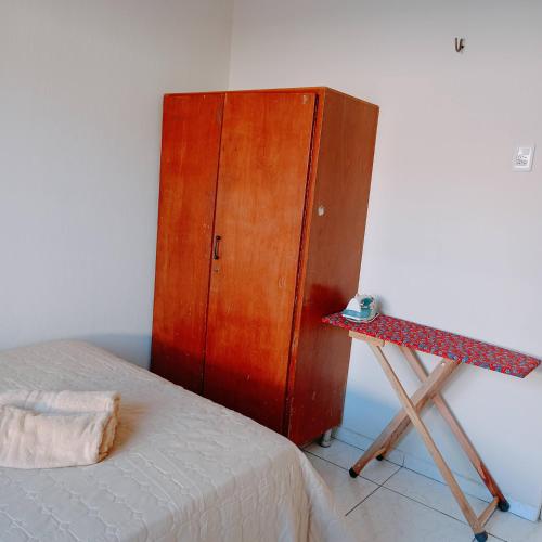 a bedroom with a wooden cabinet next to a bed at Cozy and fast Wi-Fi 15 minutes from the sea in Caucaia