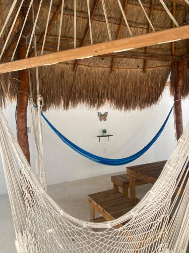 a hammock in a thatched room with a table and bench at Casa Loto B in Chelem