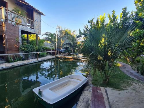 a boat sitting in the water next to a house at Chalés Refúgio Fortim in Fortim