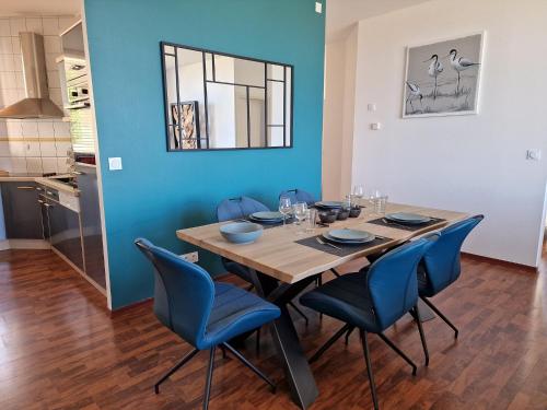 a dining room with a wooden table and blue chairs at Flat in Primel with Sea View & Beaches Nearby in Plougasnou