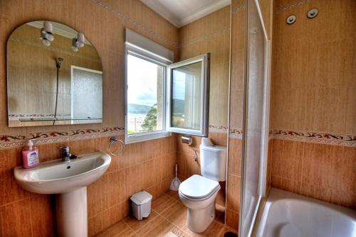 y baño con lavabo, aseo y espejo. en Pensión Mirador Fin da Terra en Finisterre