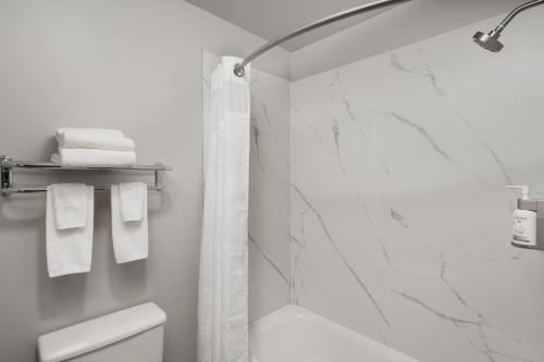 a bathroom with a shower and a toilet and towels at Garner Hotel Auburn - Seattle by IHG in Auburn