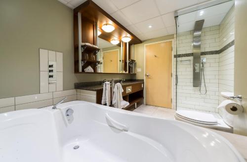 a bathroom with a tub and a toilet and a sink at Hôtel & Suites Le Dauphin Québec in Quebec City