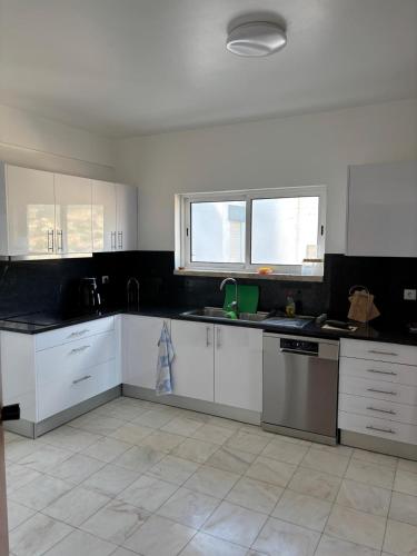 a kitchen with white cabinets and black counter tops at Casa Barcelos in Funchal