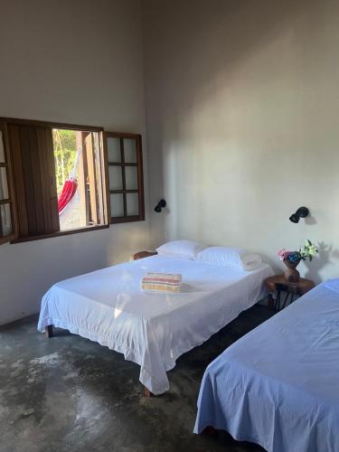 two beds in a room with a window at Hospedaria Lunar in Palmeiras
