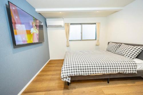 Un dormitorio con una cama y un televisor en la pared. en Hiro Yanaka hotel, en Tokio