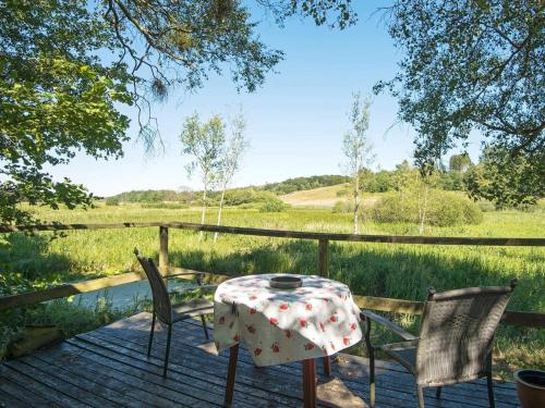 a table and chairs on a deck with a view of a field at 6 person holiday home in Brædstrup-By Traum in Brædstrup
