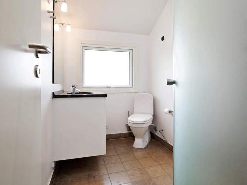 a white bathroom with a toilet and a window at Luxury Retreat with Pool - By Traum Ferienwohnungen in Marielyst