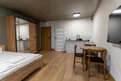 a bedroom with a bed and a table and a kitchen at Apartamenty Przystanek Morska in Gdynia