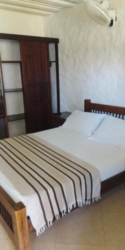 a bedroom with a bed with a striped blanket at Finca Hotel los Nogales in Quimbaya