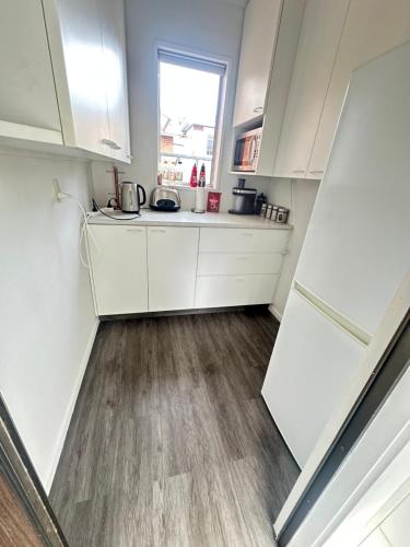 a kitchen with white cabinets and a wooden floor at Glenpark Lodge in Dunedin