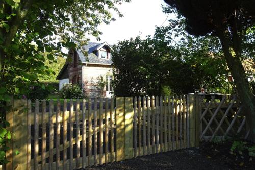 a wooden fence with a house behind it at Holiday Home near Alabaster Coast in Les Grandes-Ventes