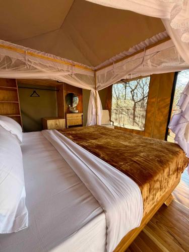 a large bed in a bedroom with a canopy at Camp Lilac Mikumi in Mikumi National Park
