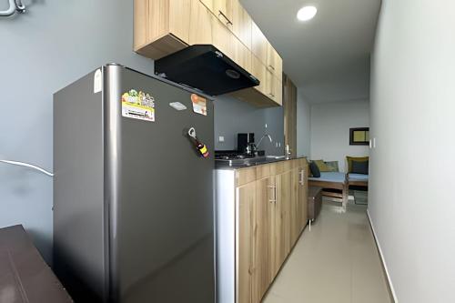 a kitchen with a stainless steel refrigerator and wooden cabinets at Studio in the Flora jacuzzi406 in Cali