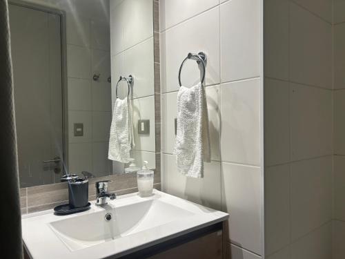 Un baño blanco con lavabo y espejo. en Eventos y Conciertos I Movistar Arena, en Santiago