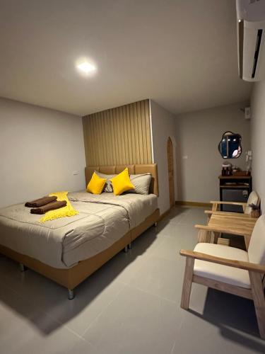 a bedroom with a bed with yellow pillows and a television at ชิลล์ แคมป์ ชะอม in Ban Bung Mai