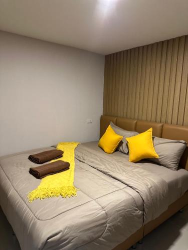 a large bed with yellow pillows and blankets at ชิลล์ แคมป์ ชะอม in Ban Bung Mai