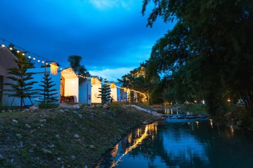 a building with lights and a river at night at ชิลล์ แคมป์ ชะอม in Ban Bung Mai