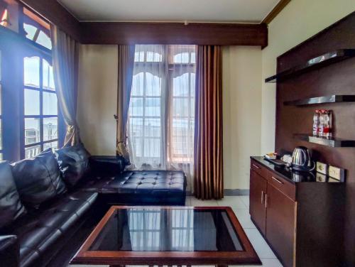 a living room with a leather couch and a large window at Hotel Nirwana Sarangan in Sarangan