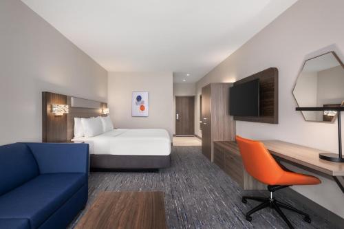 a hotel room with a bed and a blue couch at Holiday Inn Express & Suites Buford - Mall of Georgia by IHG in Buford