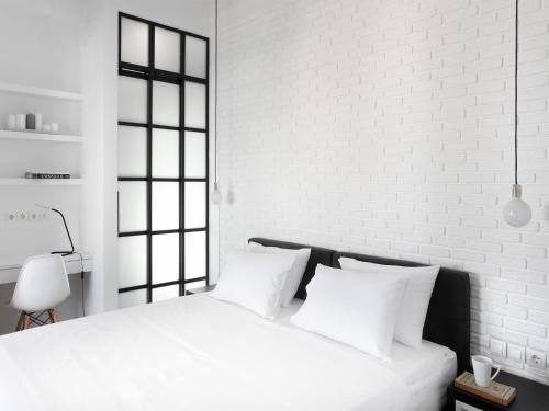 a white bedroom with a white brick wall and a bed at Athens View Loft - 06 in Athens