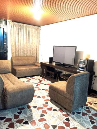 a living room with two chairs and a flat screen tv at Comodo Alojamiento en el centro de Pereira in Pereira