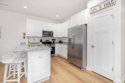 a kitchen with white cabinets and a stainless steel refrigerator at NewDuplex! 6Bed 5Bath - HotTubs - Sleeps 12! in Denver