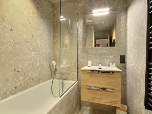 Un baño con bañera, lavabo y ducha. en Chalet neuf à La Plagne avec parking et sauna - FR-1-455-267, en La Plagne Tarentaise