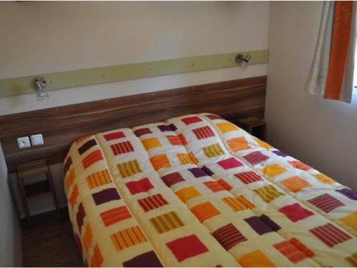 a bed with a colorful blanket on it in a bedroom at Mobil home confortable avec terrasse, espace pour 4 personnes - API-1-52-426 in Salles