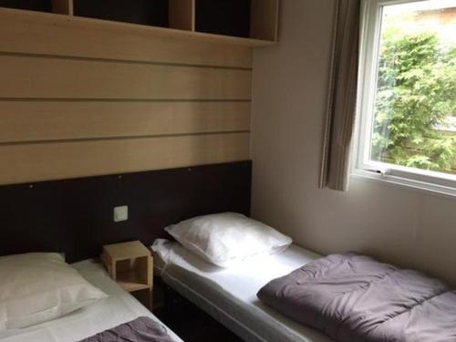 deux lits dans une chambre avec fenêtre dans l'établissement Mobil-home 30m² avec terrasse à Vendays-Montalivet - API-1-52-794, à Vendays-Montalivet