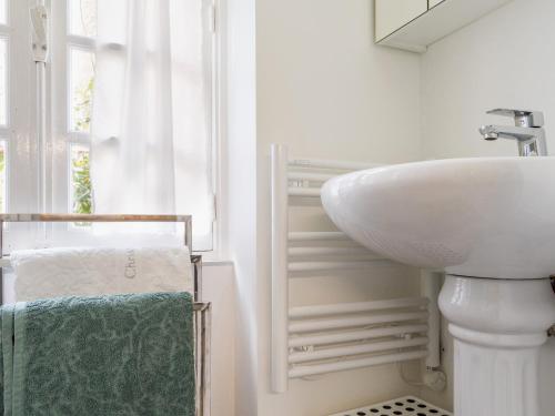 ein weißes Badezimmer mit Waschbecken und Fenster in der Unterkunft Gîte cosy près de Guérande avec Wi-Fi et terrasse - FR-1-306-1316 in Guérande