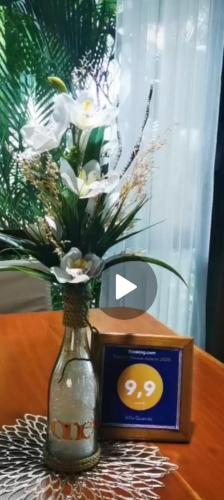 a vase with flowers in it next to a clock at Villa Guarias in Puntarenas