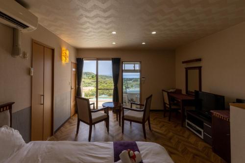 a hotel room with a bed and a table and chairs at Alpha Terrace Motobu Hills in Motobu