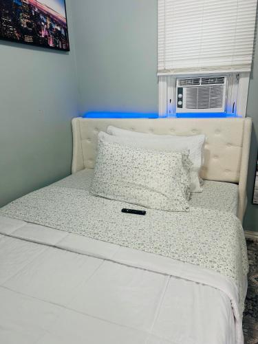 a bed with white sheets and pillows and a window at Fancy Studio Private Entrance in Selden