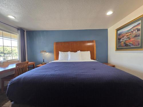 a bedroom with a large bed with a blue wall at Peach City Inn - Marysville/Yuba City in Marysville