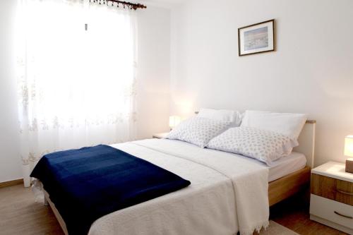 a white bedroom with a large bed and a window at Apartments Marina-Mare in Poreč