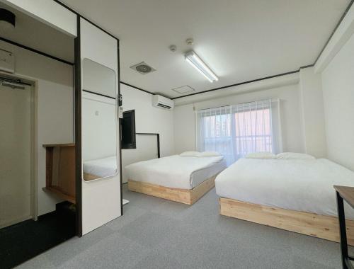 a room with two beds and a tv and a mirror at IKEBUKURO LoveSugamo 交通便利 山手線巣鴨駅徒歩3分 池袋駅4分 2ー4人 エレベーター WIFI 新宿 渋谷 銀座 浅草 銀座 原宿アクセス便利 空港直通 in Tokyo
