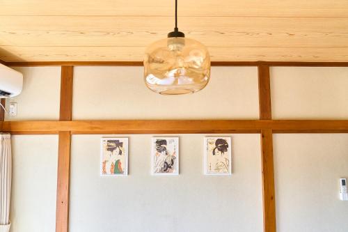 a light hanging from a ceiling with pictures on the wall at Stay as Local mizue in Tokyo