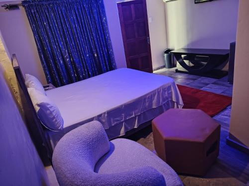 a room with a bed and a chair and a stool at Wampex Guest House in Rustenburg