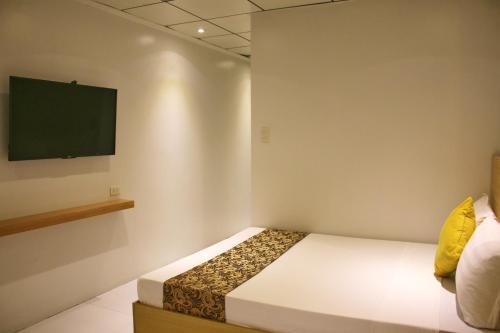 a bedroom with a bed and a flat screen tv at LuxeLite Suites Pasay in Pasay