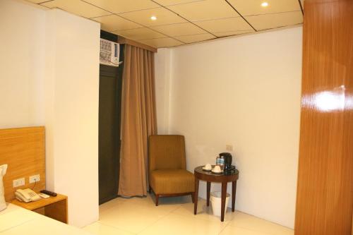 a room with a chair and a table with a phone at LuxeLite Suites Pasay in Pasay
