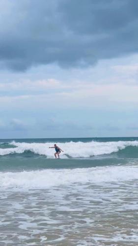 a person riding a wave on a surfboard in the ocean at Homestay Quan Lan - BLUE by MAY5 in Quan Lạn
