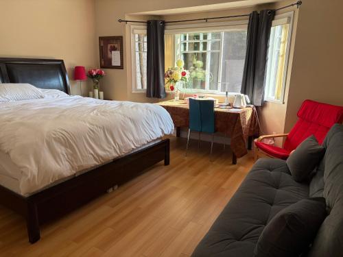 a bedroom with a bed and a couch and a table at Rose Garden Vancouver in Richmond