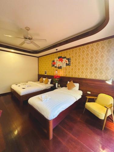 a hotel room with two beds and a chair at Mekong Charm Sunset River View in Luang Prabang