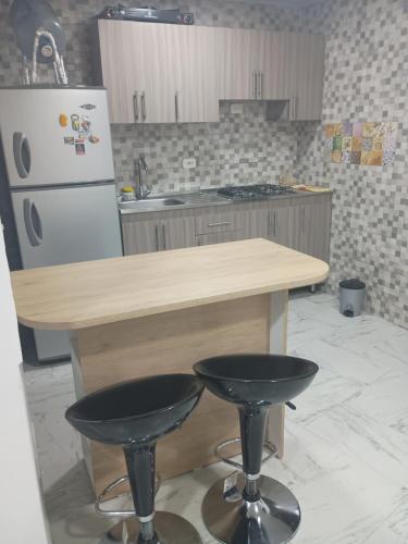 a kitchen with a counter and a refrigerator and two stools at Apartamento en Ibagué Campestre in Ibagué