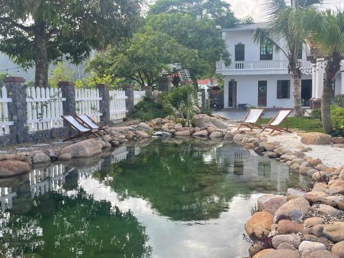 a pool of water with chairs in front of a house at Sol Flow Retreat in Nguyên Ngoại
