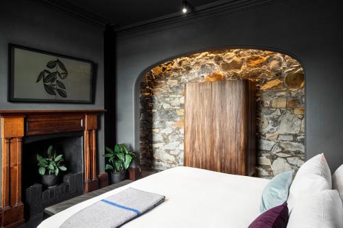 a bedroom with a stone fireplace and a bed at Stillwater Seven in Launceston